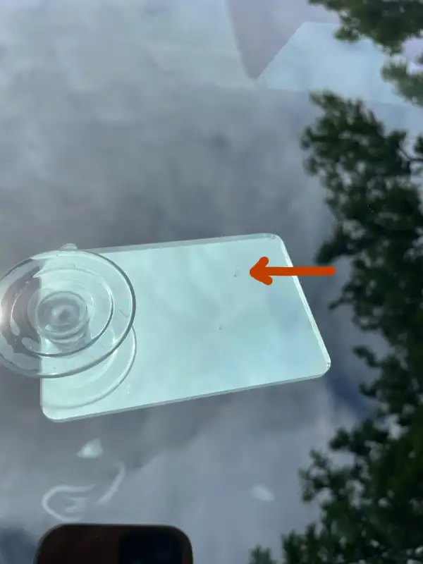 Close-up of a repaired windshield chip with a faint visible scar